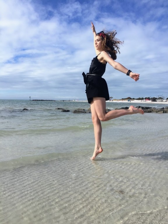 Kobieta pozująca na jednej nodze na plaży, na tle morza