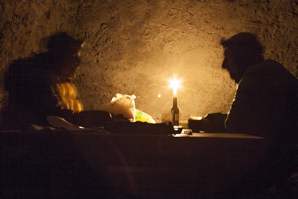 Mężczyzna z kobietą przy stole w kamiennej budowli przy blasku świecy
