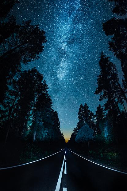 Zdjęcie drogi pomiędzy lasem w gwieździstą noc