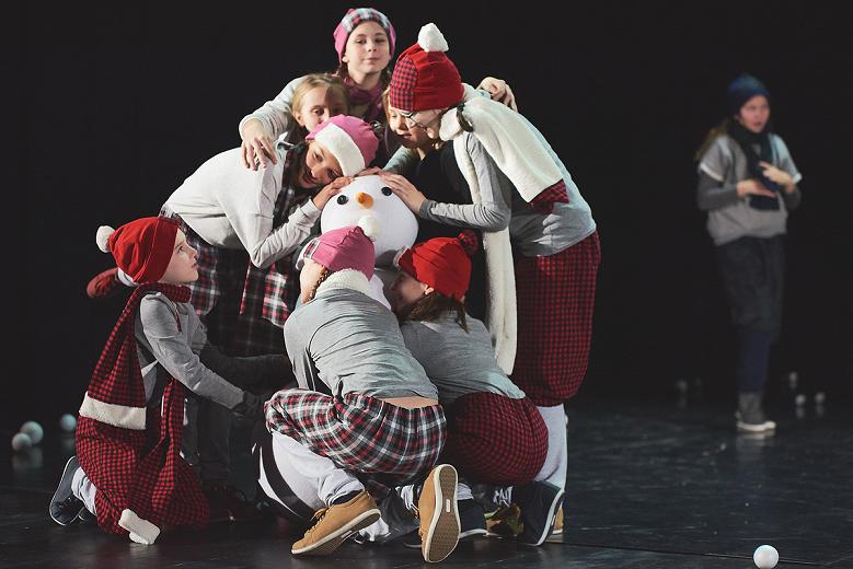 Zimowo poubierane dzieci przytulają sztucznego bałwana na scenie