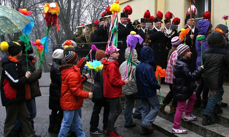 Dzieci w kurtkach idące do domu kultury, obok nich stoi orkiestra górnicza