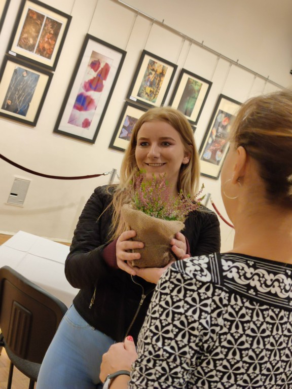 Organizatorka wręczająca kwiaty autorce prac w Galerii Kolumnowej