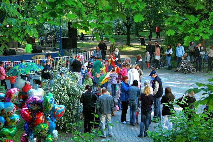 Grupa ludzi w parku, po lewej stronie zawieszone kolorowe balony