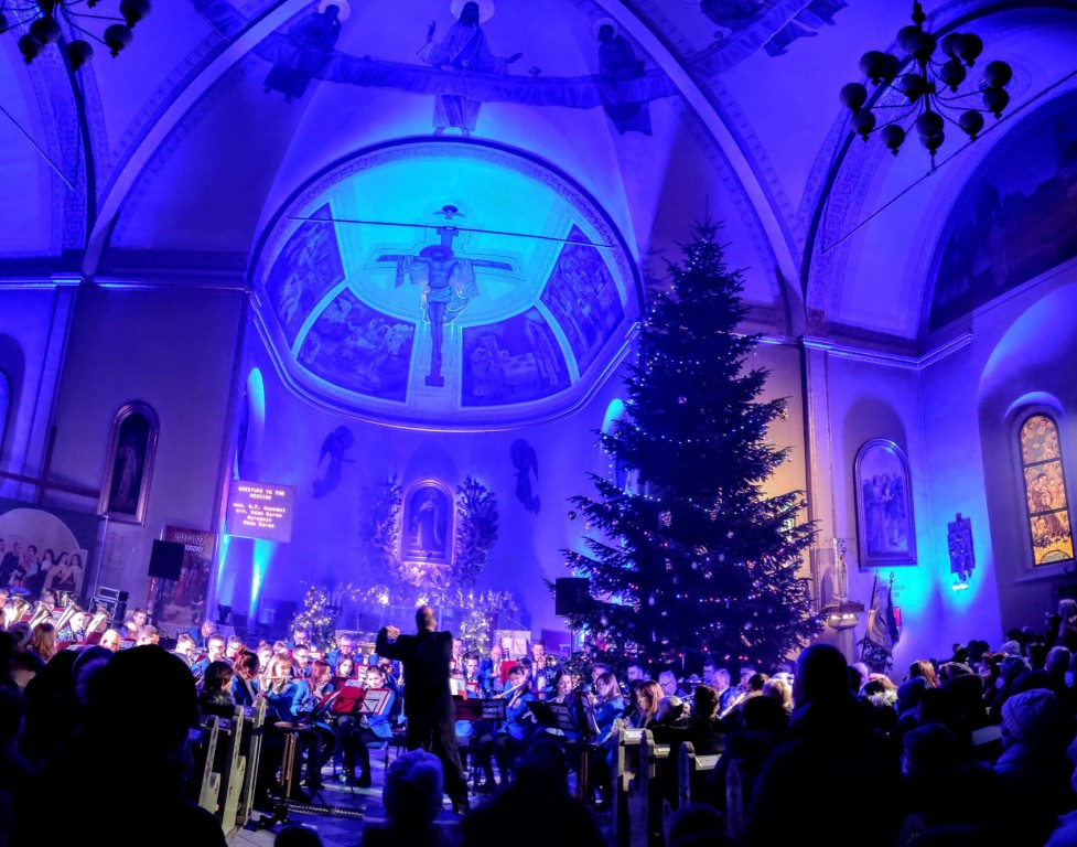 orkiestra oraz wierni na tle oświetlonego kościoła