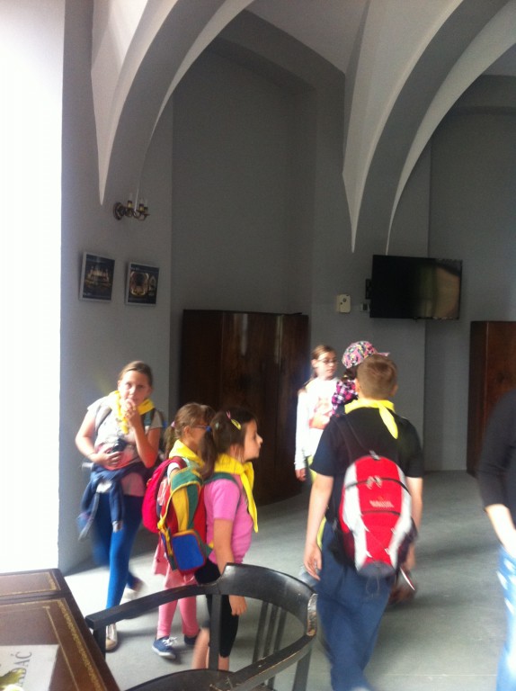 Dzieci w żółtych chustach z opiekunami w muzeum