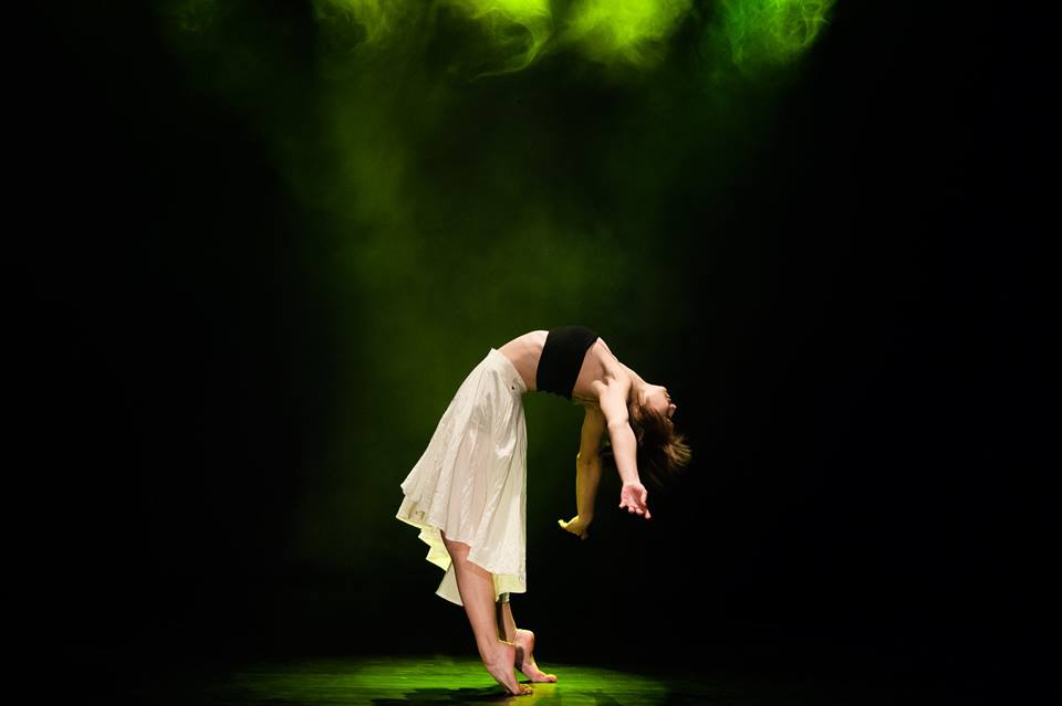 Tancerka występuje na scenie, za nią zielone światła