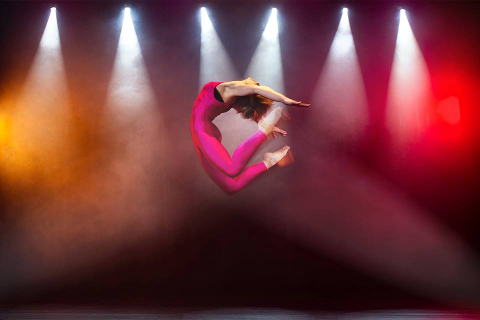 Tancerka w różowym ubraniu skacząca w górę