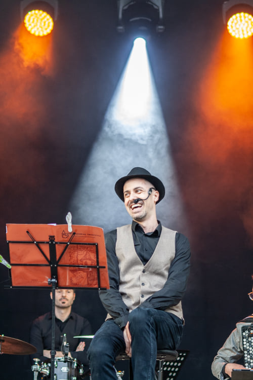 Mężczyzna siedzi na krześle na scenie, przed sobą ma stojak na nuty