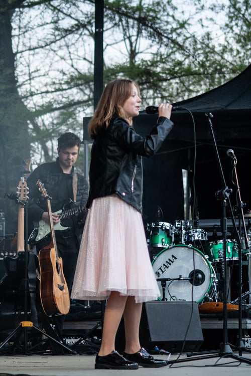 Dziewczynka śpiewa na scenie, w tle widać gitarzystę