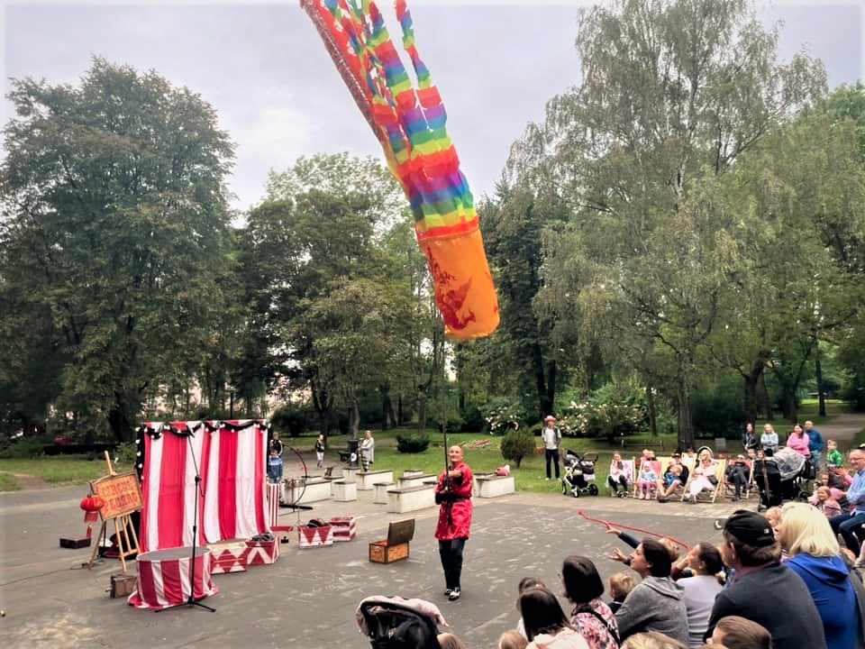 Osoba trzymająca wielki kolorowy balon na sznurku przed widownią w parku