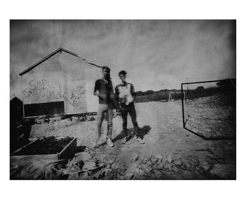 Czarno białe zdjęcie dwóch osób stojących przy budynku