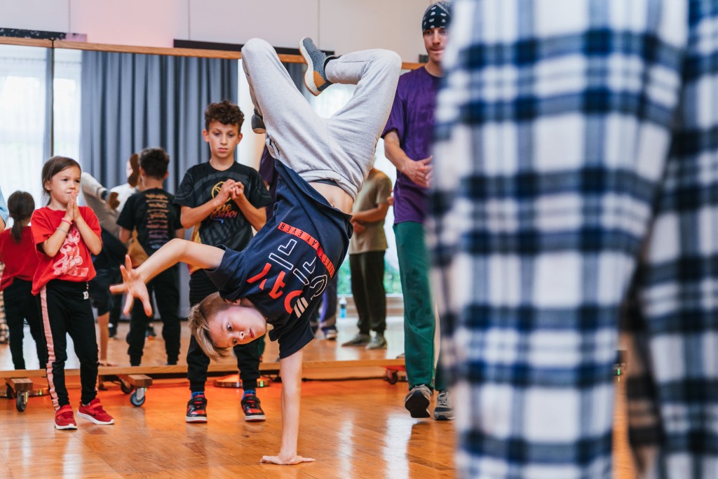 Chłopak stojący na jednej ręce, inni ludzie na niego patrzą