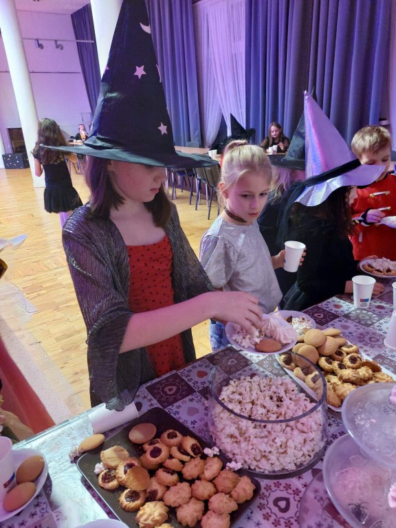 dzieci częstują sie słodyczmi przy stole