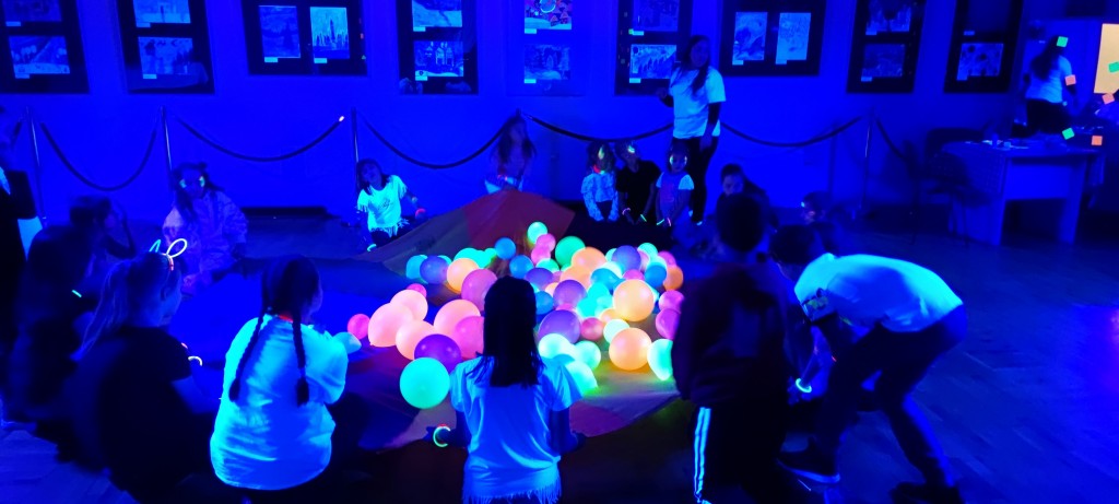 Zdjęcie przedstawia dzieci oraz neonowe balony