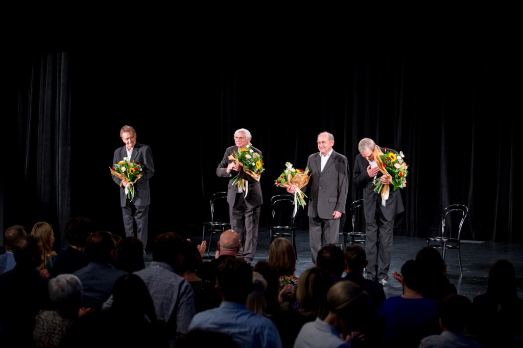 Czterej mężczyźni trzymają kwiaty i kłaniają się na scenie