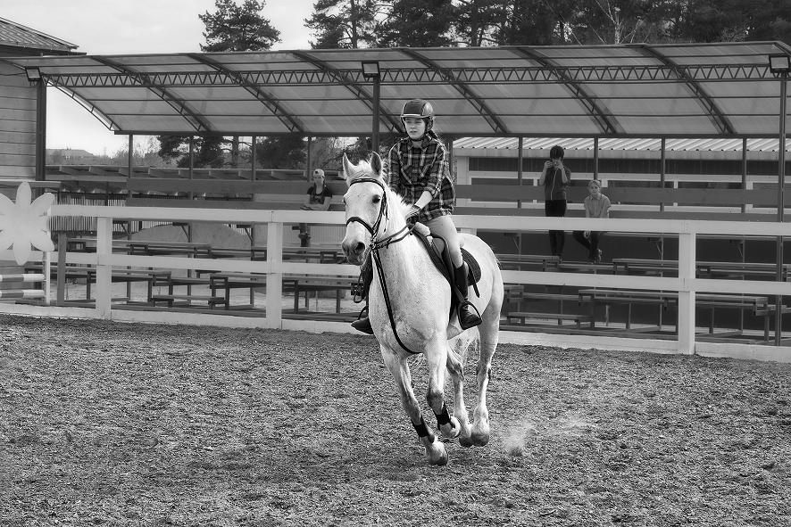 Czarno-białe zdjęcie osoby jadącej na białym koniu