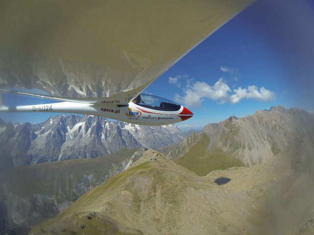 Zdjęcie spod skrzydła samolotu nad górzystym terenem