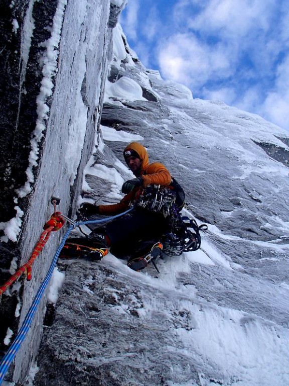 Alpinista wspinający się po stromym zboczu lodowej góry