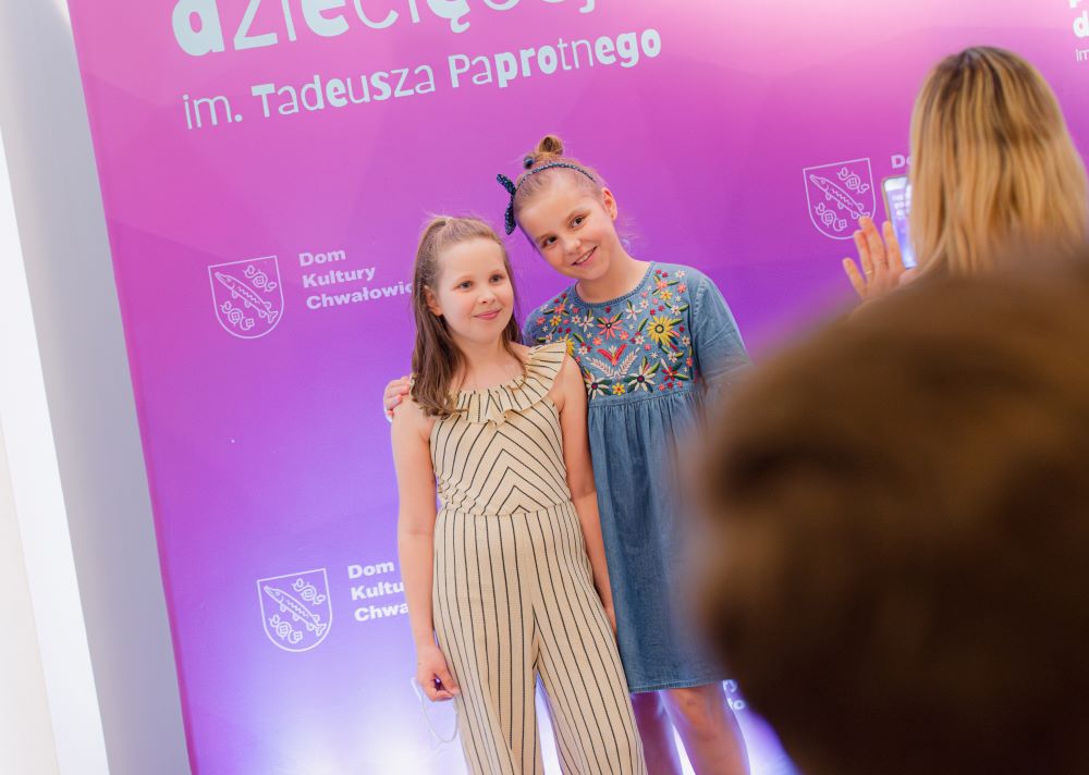 dwie dziewczynki pozują na tle fioletowej ścianki