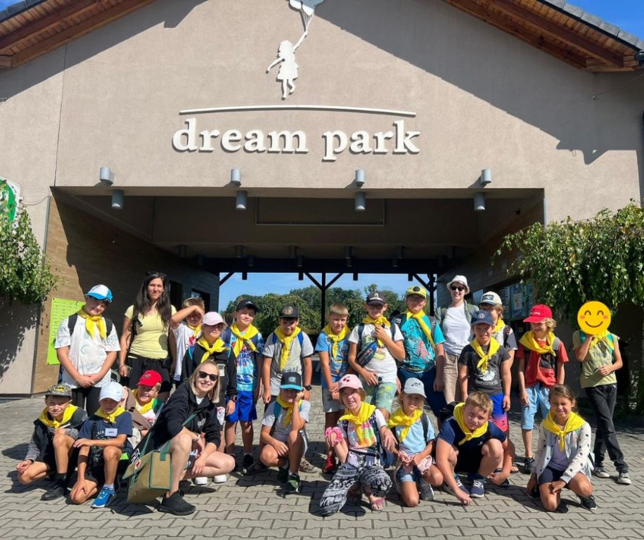 Dzieci na wycieczce stoją wraz z opiekunami przed wejściem do dream parku.