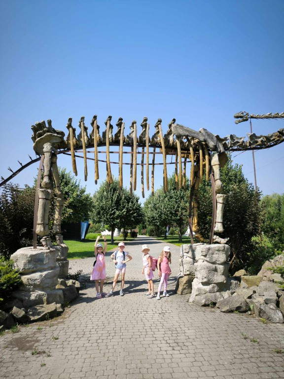 Dzieci stoją pod ogromnym szkieletem dinozaura.