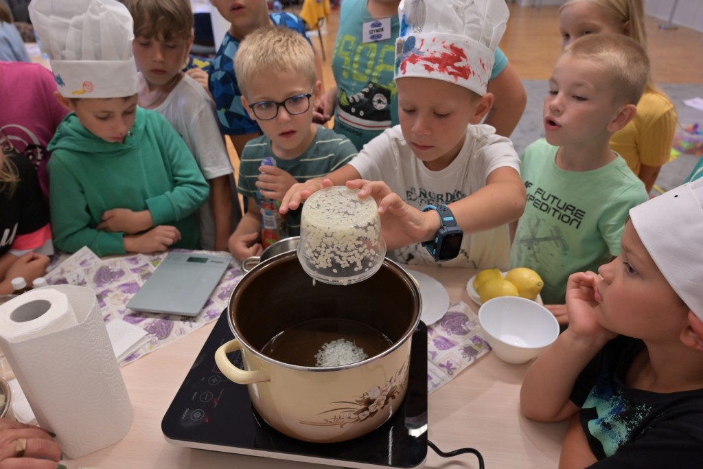 Dzieci wrzucają składniki do garnka.