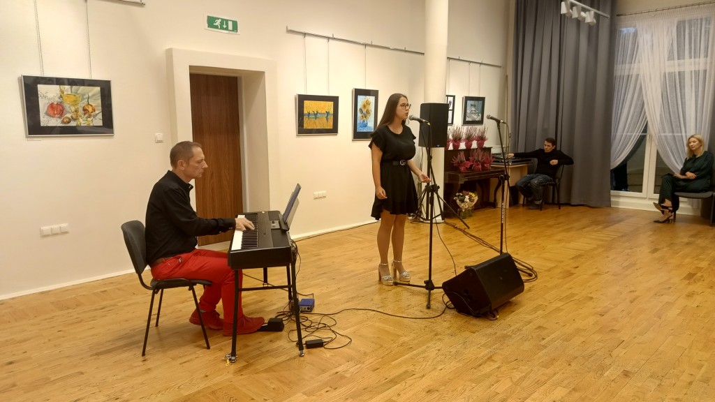 Kobieta śpiewa, a mężczyzna obok gra na keyboardzie.