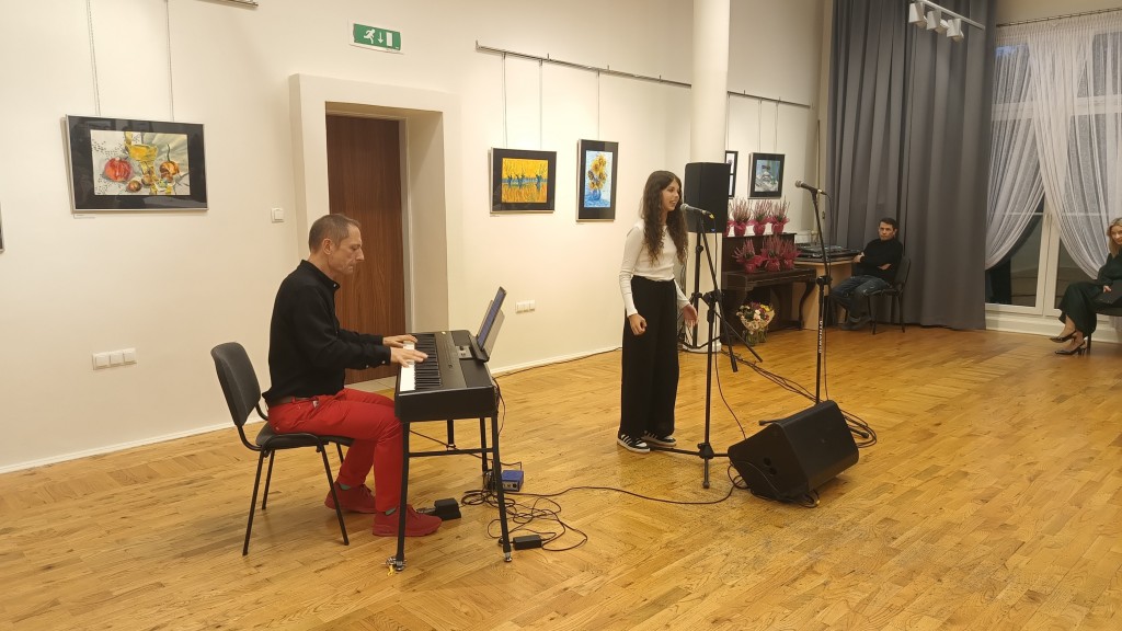Dziewczyna śpiewa, a mężczyzna obok gra na keyboardzie.