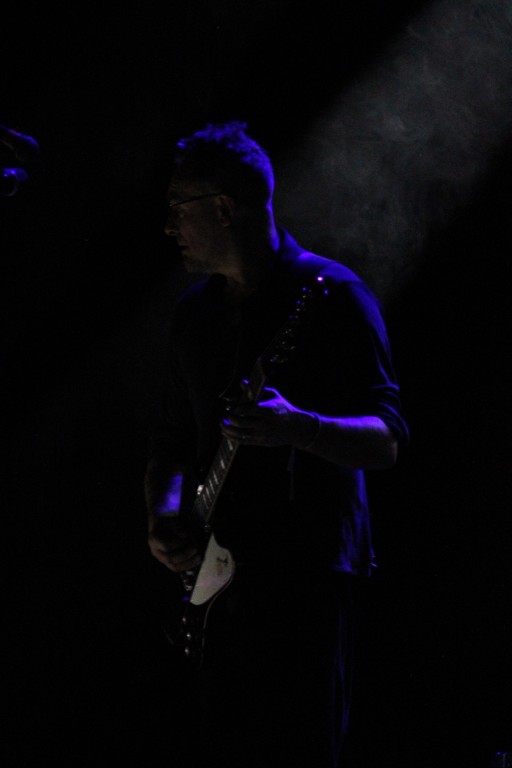 Występ sceniczny. Gitarzysta w półmroku.