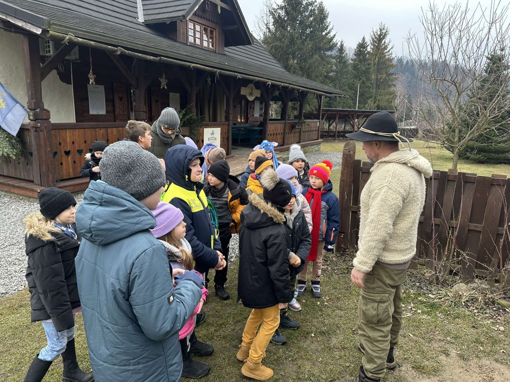 zdjęcie grupowe, mężczyzna w stroju góralskim opowiada coś dzieciom