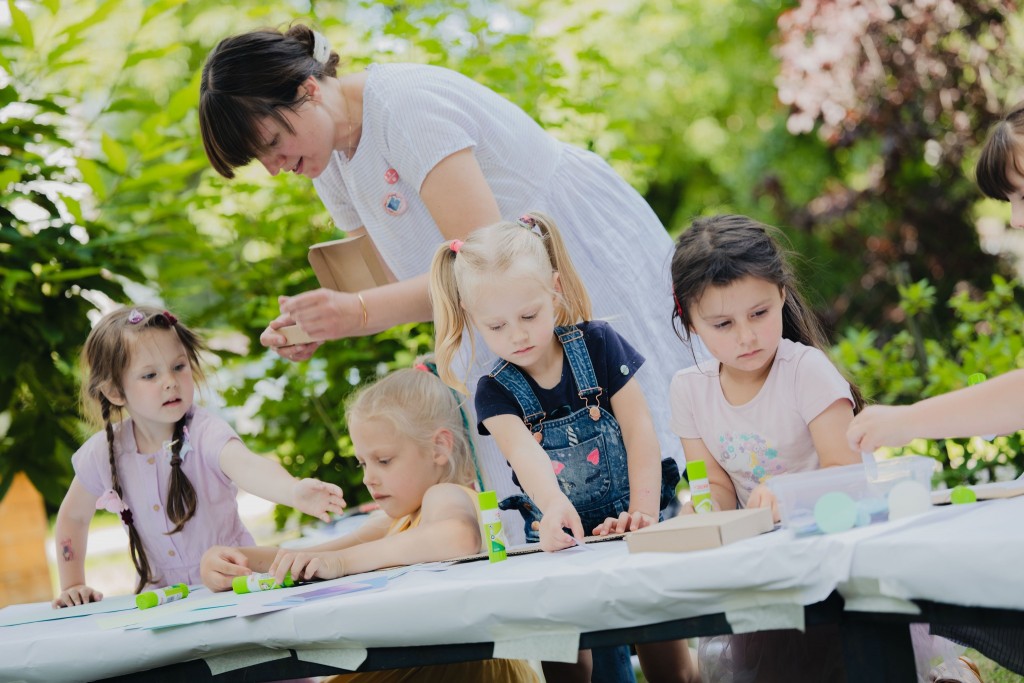 Małe dziewczynki uczestniczą w zajęciach plastycznych na świeżym powietrzu.