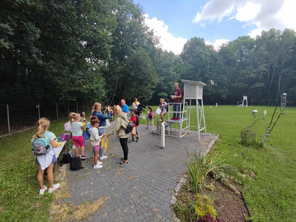 Dzieci stoją w grupie z opiekunami.