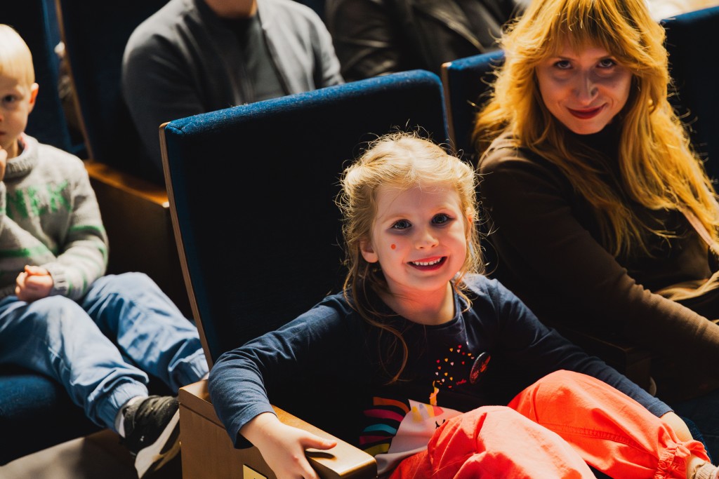 przed spektaklem, mała dziewczynka na widowni uśmiecha się w kierunku fotografa