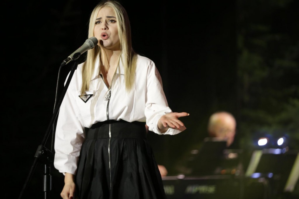 młoda dziewczyna podczas występu scenicznego, w tle zespół