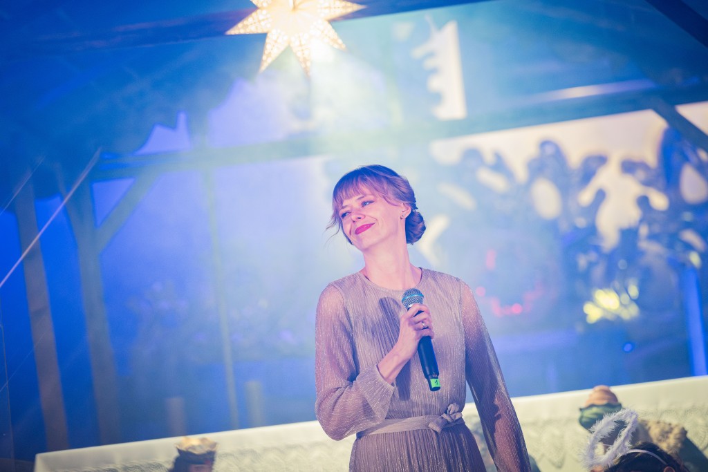 Kobieta z mikrofonem, patrzy w jedną stronę i się uśmiecha.