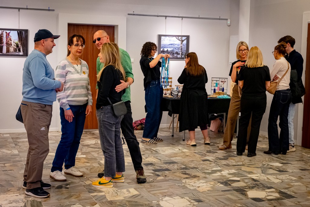 Grupki osób rozmawiające w hol, w tle widać wystawę.