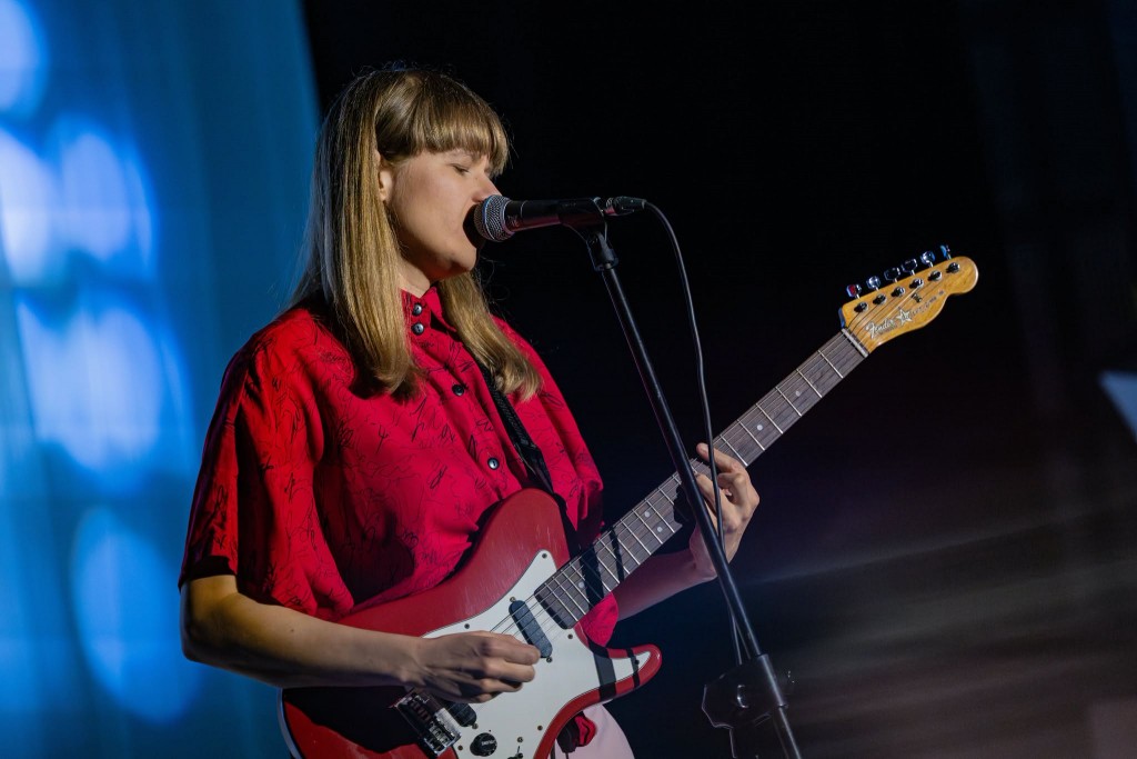 sytuacja sceniczna, kobieta śpiewa i gra na gitarze