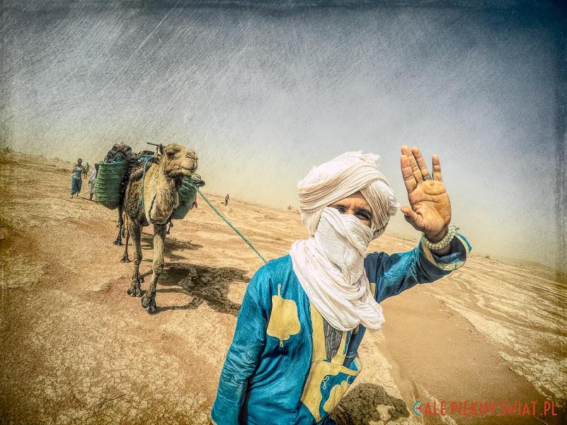 mężczyzna w turbanie z wielbłądem na pustyni