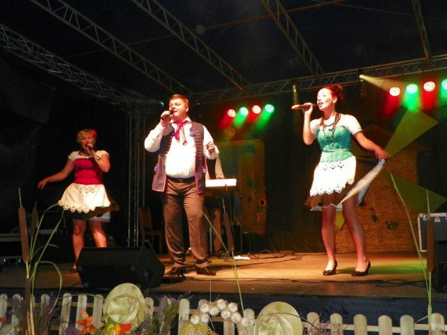 dwie kobiety i mężczyzna w stroju ludowym na scenie śpiewają