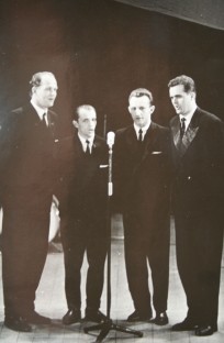 Czterech mężczyzn stojących przed mikrofonem