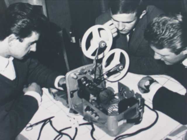 Troje mężczyzn oglądających małą maszynę na stole