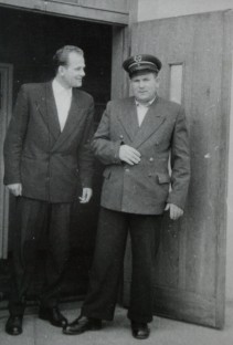 Dwoje mężczyzn ubranych elegancko stoi obok siebie, jeden z nich ma założoną policyjną czapkę