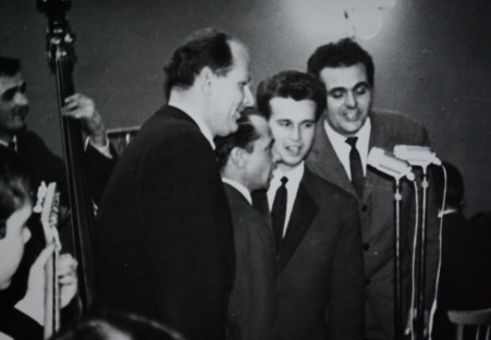 Parę mężczyzn stojących przed występującymi muzycznie ludźmi