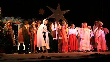Aktorzy dzieci stojące w grupie na scenie trzymający nad sobą dużą gwiazdkę