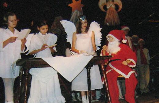 Dziewczynki przebrane za anioły stojące przy chłopcu przebranym za świętego Mikołaja