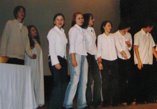 Ludzie ubrani w białe koszule śpiewający na scenie