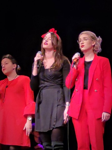 trzy kobiety śpiewające na scenie
