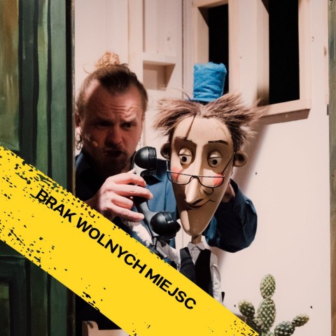 sytuacja sceniczna, aktor trzyma lalkę, która rozmawia przez telefon.