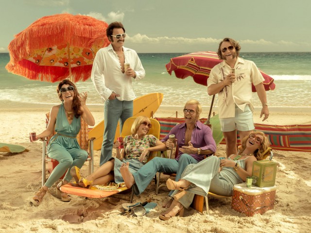 grupa sześciu osób na plaży, na leżakach, styl lat 70tych XX wieku.