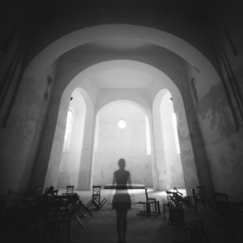 Czarno-białe zdjęcie wnętrza budynku, na środku widać cień kobiety